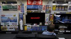 A man sitting on a sofa looks at a Sharp Corp's Aquos TV at an electronics retailer in Tokyo