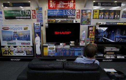 A man sitting on a sofa looks at a Sharp Corp's Aquos TV at an electronics retailer in Tokyo