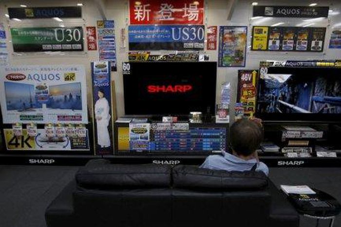 A man sitting on a sofa looks at a Sharp Corp's Aquos TV at an electronics retailer in Tokyo
