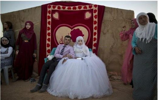 Ahmad Khalid and his bride, Fatheya Mohammed, both 21, sit in front of his family's tent during their wedding ceremony in an informal tent settlement on the outskirts of Mafraq, Jordan, near the Syrian border, on Aug. 7.