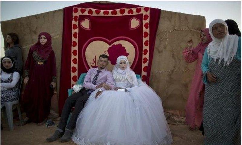 Ahmad Khalid and his bride, Fatheya Mohammed, both 21, sit in front of his family's tent during their wedding ceremony in an informal tent settlement on the outskirts of Mafraq, Jordan, near the Syrian border, on Aug. 7.