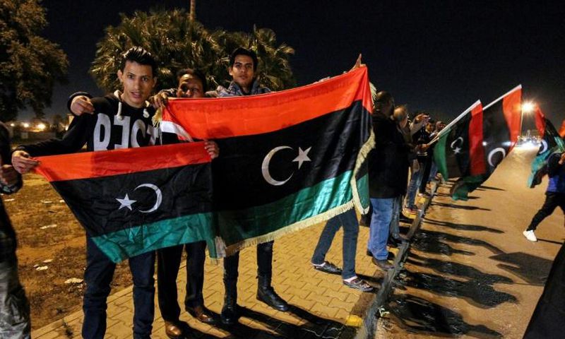 Libyans hold their national flags during a celebration marking the seventh anniversary of the revolution which toppled and killed veteran strongman Moamer Kadhafi in the eastern city of Benghazi on February 17, 2018