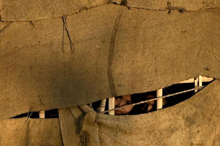 Rohingya refugee girls peep out from a makeshift shelter at Balukhali refugee camp in Ukhia, Bangladesh
