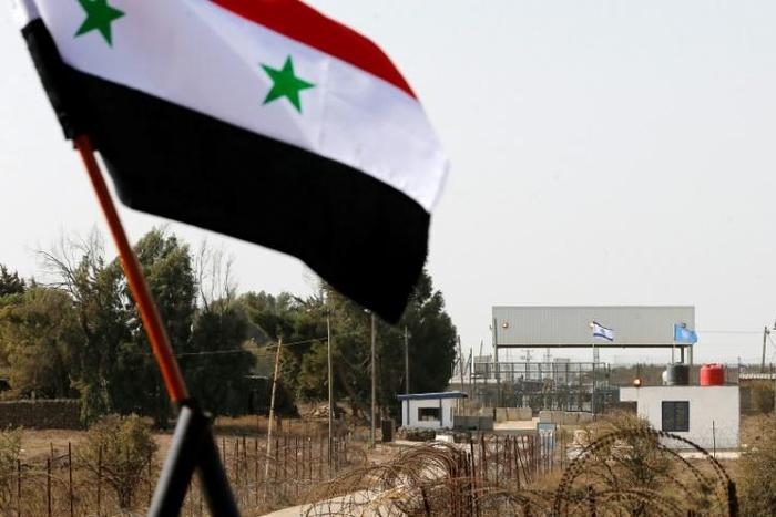 The Syrian national flag flies in front the Quneitra border crossing into the Israeli annexed-Golan Heights