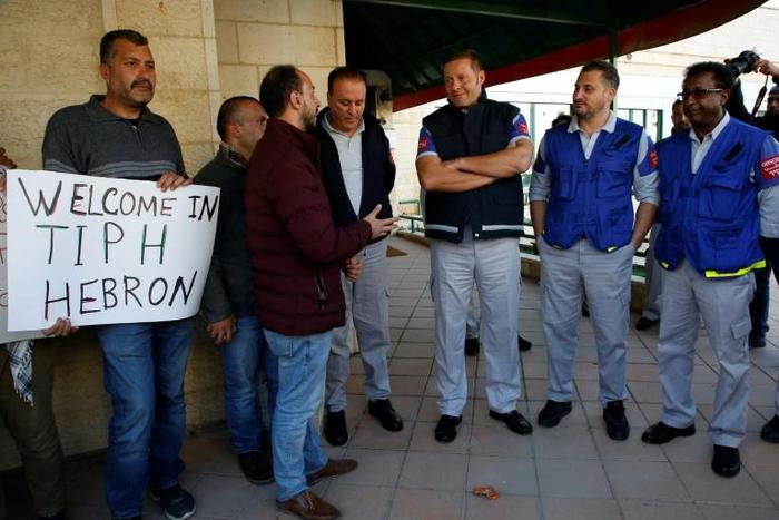 Observers from The Temporary International Presence in Hebron (R, pictured January 2019) stand next to Palestinians carrying placards denouncing the Israeli prime minister's recent decision not to renew their mandate, a move Turkey has also denounced
