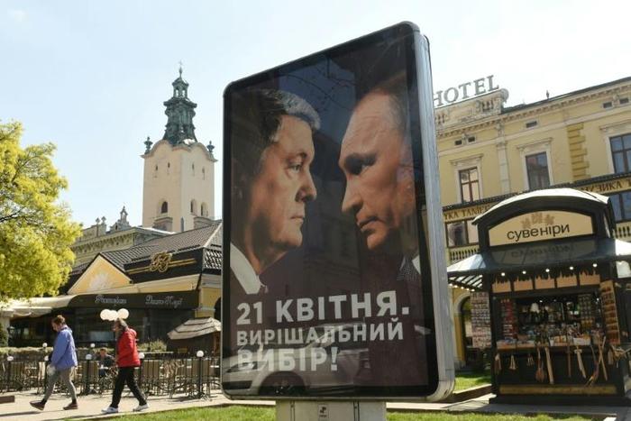 A campaign billboard reads "April 21st. Decisive choice!", bearing the portraits of Ukrainian President Petro Poroshenko and Russian President Vladimir Putin in the center of the western Ukrainian city of Lviv