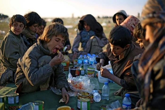 Yezidi boys share a meal in Syrian Democratic Forces-held territory after escaping the last scrap of the Islamic State group's collapsed "caliphate"