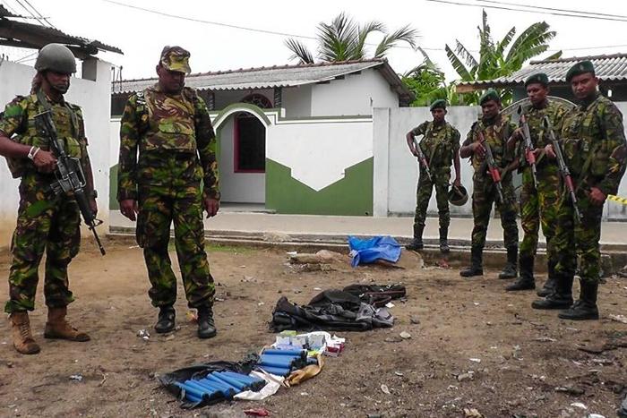 Soldiers look at seized items at the site of an overnight battle between Sri Lankan security forces and suicide bombers in the eastern town of Kalmunai