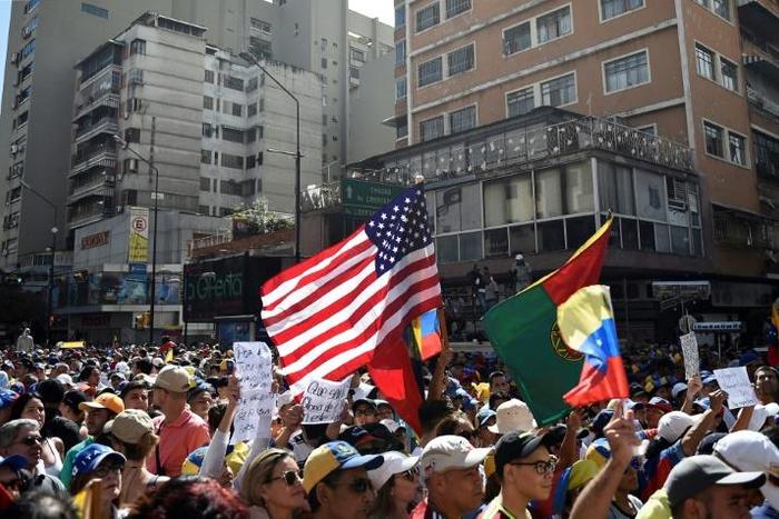 A US flag is seen amid the crowd of supporters of Venezuelan opposition leader Juan Guaido, as people start gathering for a rally to press the military to let in US humanitarian aid, in Caracas on February 12, 2019
