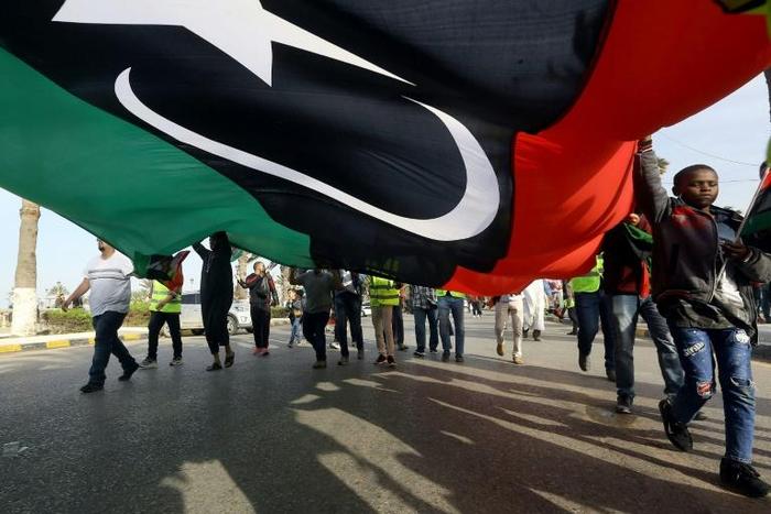 Libyans wave a giant national flag during a demonstration in Tripoli on Friday, in protest against strongman Khalifa Haftar