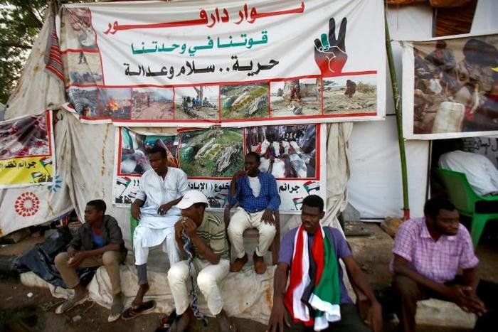 Sudanese men displaced from Darfur sit next to a tent outside the military headquarters in the capital Khartoum at the ongoing sit-in