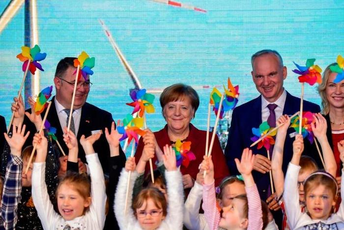 German Chancellor Angela Merkel joined Norway's Minister of Petroleum and Energy Kjell Borge Freiberg (left) and the chairman of energy group E.ON Johannes Teyssen (right) and a group of schoolchildren to open the new wind park