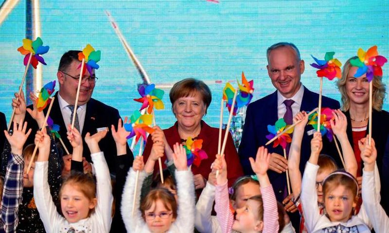 German Chancellor Angela Merkel joined Norway's Minister of Petroleum and Energy Kjell Borge Freiberg (left) and the chairman of energy group E.ON Johannes Teyssen (right) and a group of schoolchildren to open the new wind park