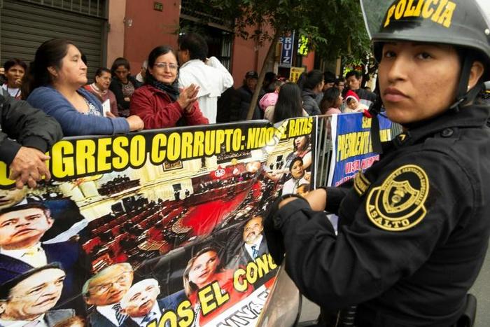 "Corrupt Congress: Nest of Rats" reads the sign held by demonstrators outside Peru's single-chamber legislature, with pictures of prominent lawmakers