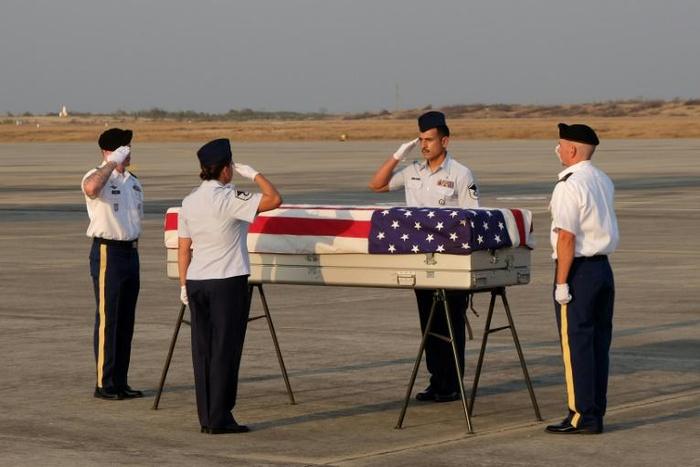 A US military honour guard salutes the flag-draped coffin bearing the recovered remains of suspected American World War II airmen during a repatriation ceremony at the Mandalay International Airport on Tuesday