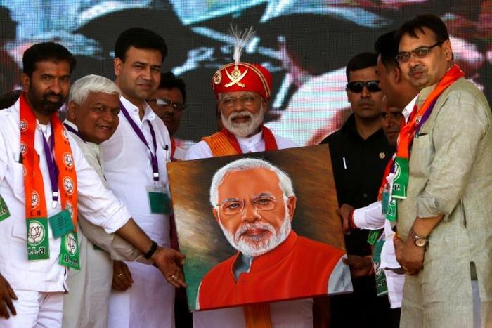 Indian Prime Minister Narendra Modi (C) holds a canvas displaying a portrait of himself during an election rally in Chittorgarh, in the western state of Rajasthan -- Modi will vote in his home state of Gujarat on "Super Tuesday"