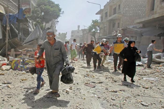 Members of the Syrian Civil Defence (known as the White Helmets) carry a wounded man on a stretcher after a reported air strike Maaret al-Numan in the jihadist-held Idlib province as others flee the scene