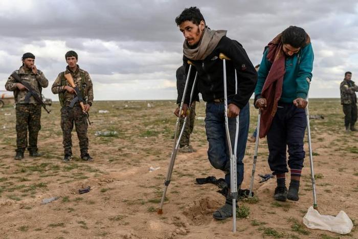 Men and boys suspected of being Islamic State fighters wait to be searched by members of the Kurdish-led Syrian Democratic Forces after leaving the IS group's last holdout of Baghouz on February 27, 2019