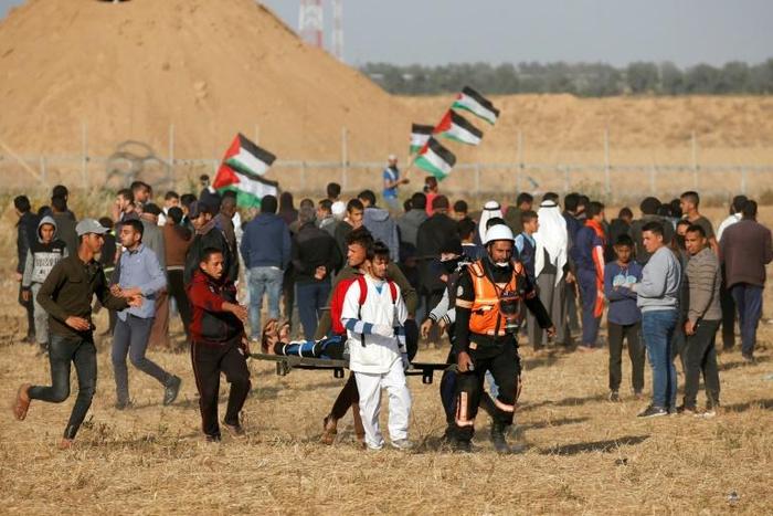 Palestinian paramedics carry a wounded protester during a demonstration near the border between Israel and the Gaza Strip on April 12, 2019