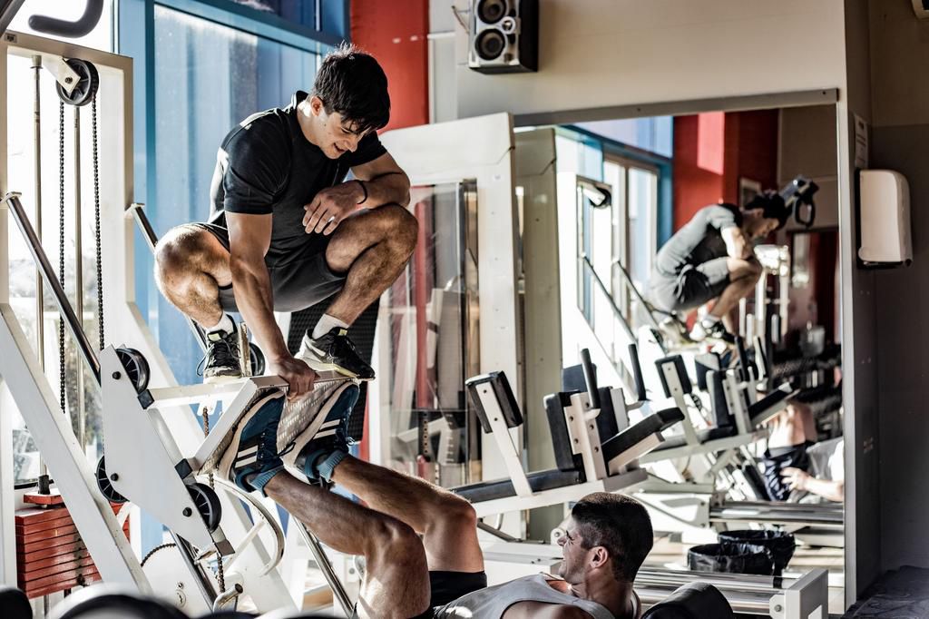 Fitness Instructor Assisting a Young Man at Weight Training