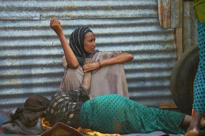 An elderly woman weakened by hunger lies on the ground as her daughter watches over her at a camp for the internally displaced on the outskirts of Baidoa town, the capital of Bay region of south-western Somalia