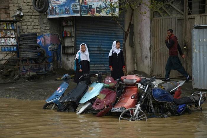 Pedestrians look for dry ground on a street after heavy rains in Kabul