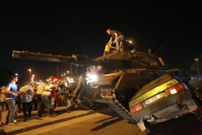 Turkish pro-regime supporters climb onto a tank as it runs over a car during a protest against the military in Ankara on July 16, 2016