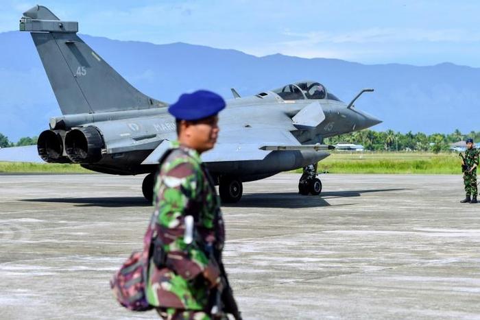 Indonesian soldiers stand guard near one of the seven French fighter jets which were forced to make an emergency landing due to bad weather