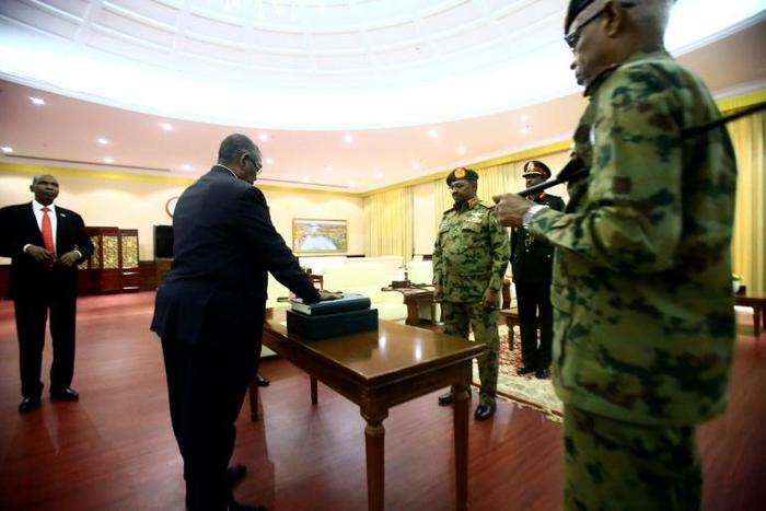 Sudanese President Omar al-Bashir (3rd-R) swears in Mohamed Tahir Ela (2nd-L) as the country's new prime minister on February 24, 2019 amid protests against the veteran president's rule and calls for him to resign