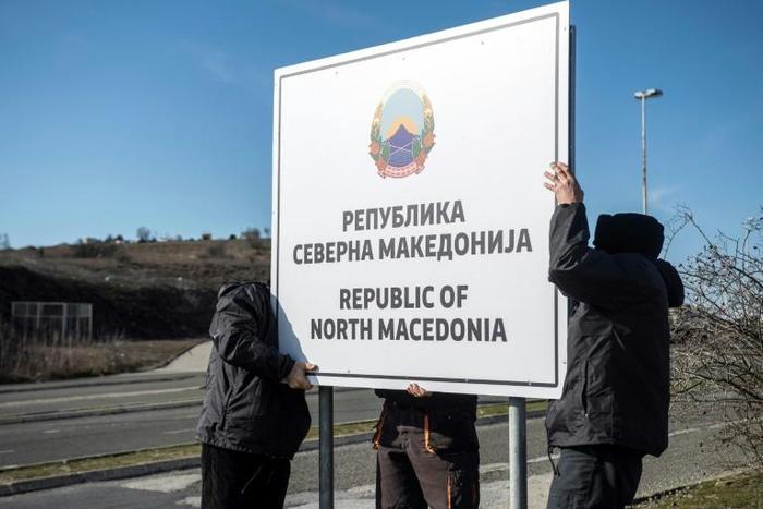 Workers set up a sign reading 'Republic of North Macedonia' at the Macedonia-Greece border near Gevgelija on February 13, 2019