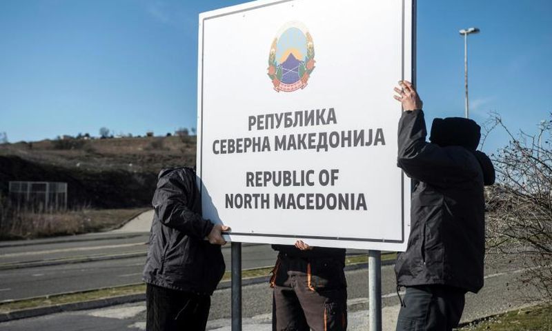 Workers set up a sign reading 'Republic of North Macedonia' at the Macedonia-Greece border near Gevgelija on February 13, 2019