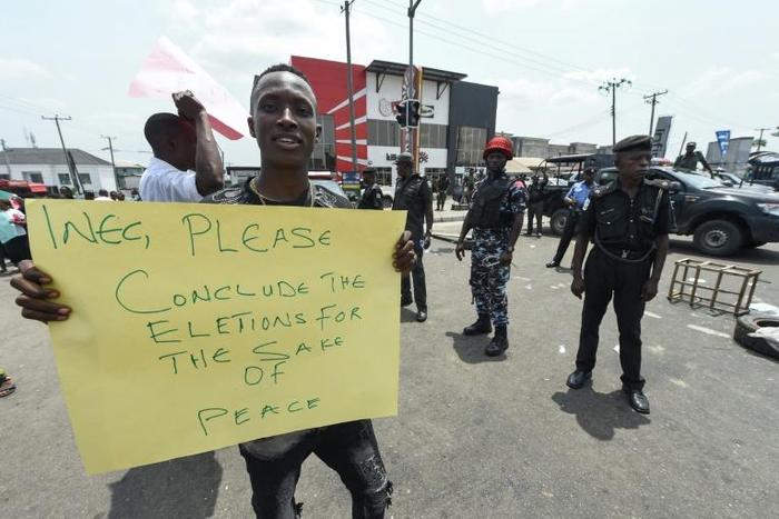 A protester holds a placard reading "Please conclude the elections for the sake of peace" during a demonstration against the suspension of governorship elections in Port Harcourt, Rivers state