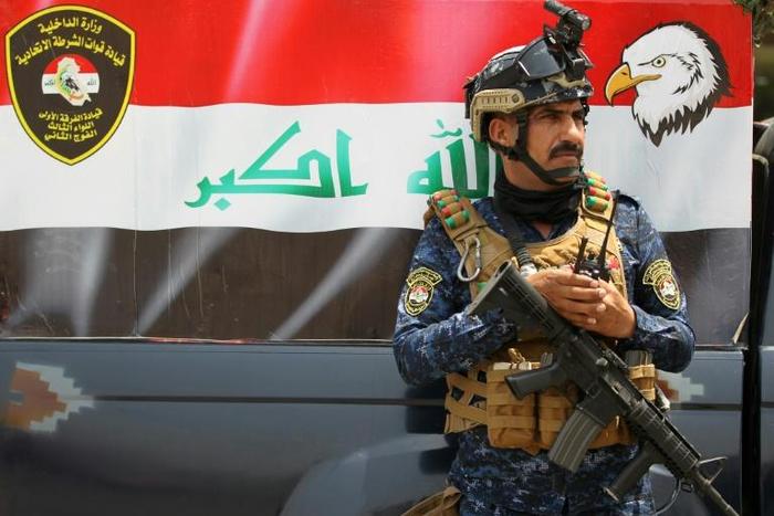 A member of the Iraqi federal police forces stands guard at a checkpoint in Baghdad's Karada district