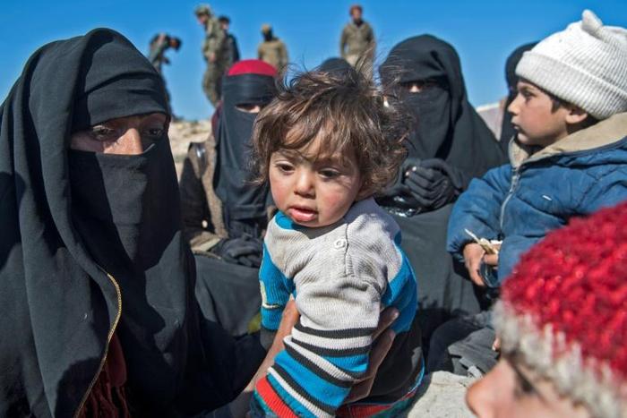 Fully veiled women and children gather after fleeing from the Baghouz area in the eastern Syrian province of Deir Ezzor on February 12, 2019 during an operation by the US-backed Syrian Democratic Forces (SDF) against the Islamic State group