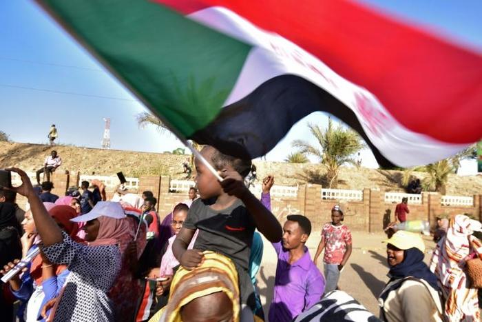 A young Sudanese boy waves a national flag as people celebrate concessions by Sudan's new military ruler, in Khartoum, on Saturday
