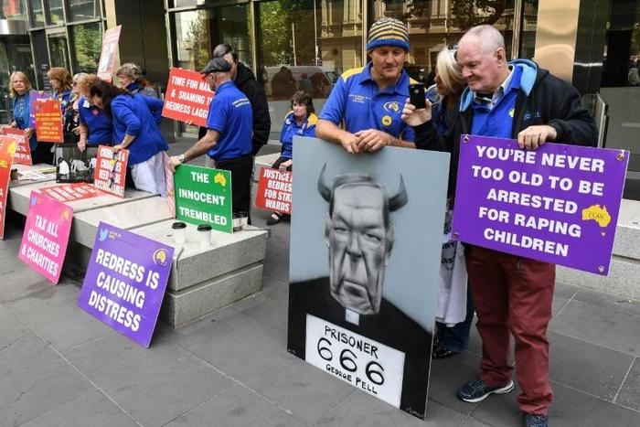 Protesters hold placards outside the court ahead of the sentencing of Cardinal George Pell in Melbourne on Wednesday