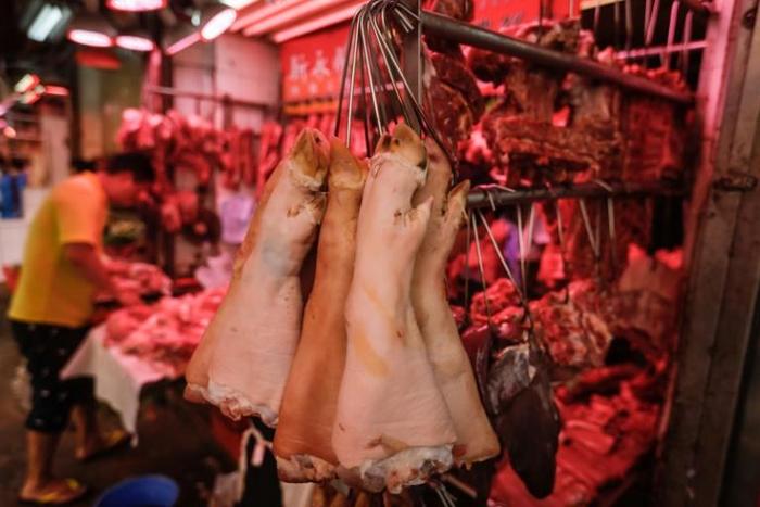 Pig trotters hang from hooks at a meat market in Hong Kong, where the price of pork has soared since the outbreak of African swine fever