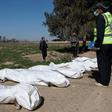 Workers gather bodies found in another mass grave near the northern Syrian city of Raqa on February 19, 2019