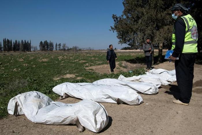 Workers gather bodies found in another mass grave near the northern Syrian city of Raqa on February 19, 2019