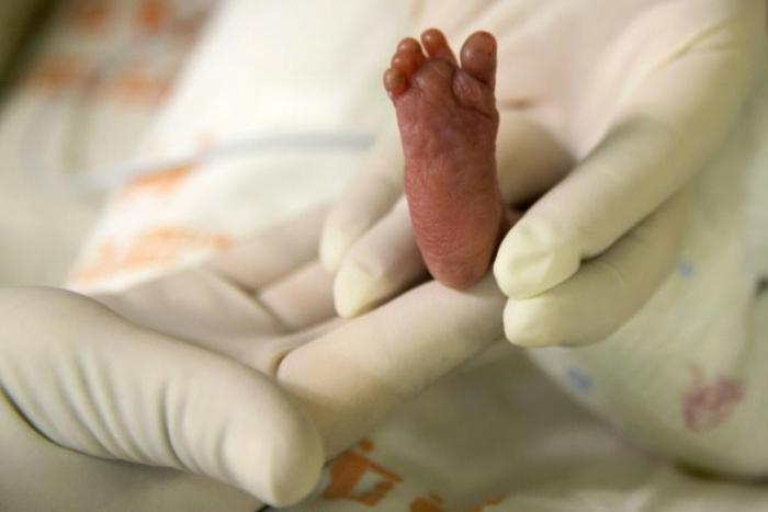 A pediatric nurse holds a premature baby after feeding him at Medellín's General hospital on August 20, 2014 in Medellin, Colombia. A Greek mother of the first baby born using DNA from three people has praised the revolutionary technique