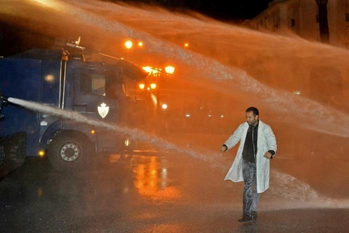 A Moroccan teacher walks through a water cannon during a demonstration calling for permanent contracts