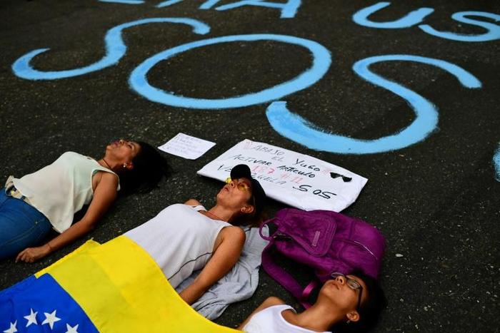 Opponents to the government of Venezuelan President Nicolas Maduro with a Venezuelan national flag block a street as they demonstrate in Caracas on March 12, 2019