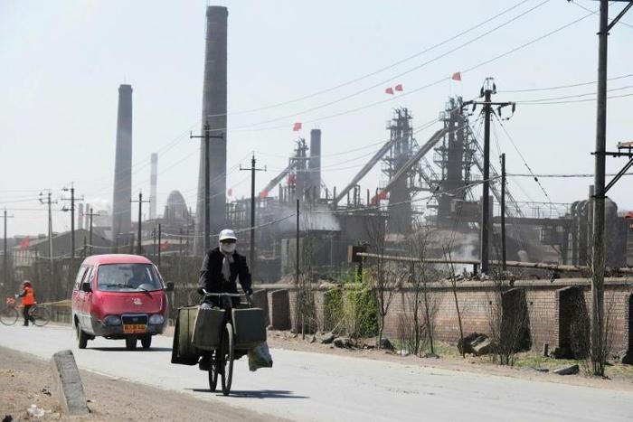 A cyclist is pictured in 2011 riding along a dusty road where dozens of factories process rare earths, iron and coal on the outskirts of Baotou city in Inner Monglia, northwest China
