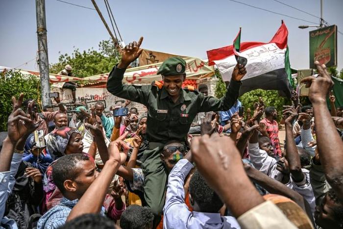 A Sudanese soldier joins protesters outside the army complex in Khartoum