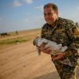 A member of the Kurdish-led Syrian Democratic Forces (SDF) carries a baby followed by a woman who fled the Islamic State (IS) group's last holdout of Baghouz, in northern Syria's Deir Ezzor province
