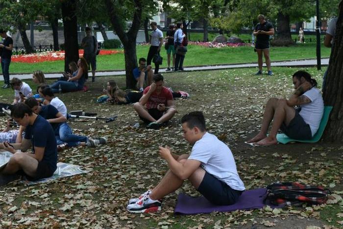 People look at their smartphones in central Moscow in August 2016 -- dating app Tinder has now been required to register with Russian security services
