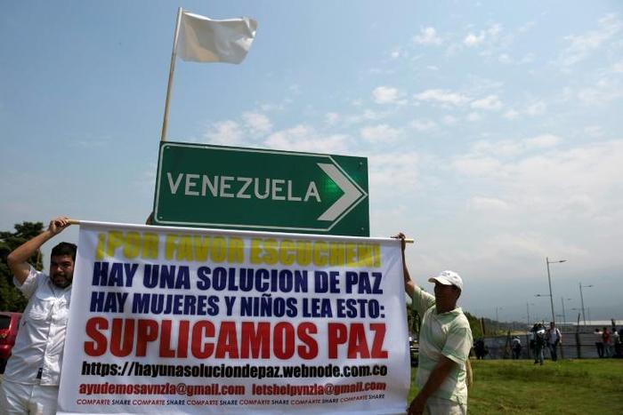 Men protest with a sign calling for peace near the Tienditas Bridge which links Venezuela and Colombia, after Venezuelan military forces blocked it