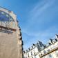 A trompe l'oeil shows two workers painting the European Union flag on the side of a building in Paris