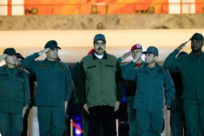 This handout picture released by Miraflores Palace press office shows Venezuela's President Nicolas Maduro (C) receiving a salute from troops at the "Fuerte Tiuna" military headquarters in Caracas, Venezuela