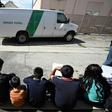 Central American asylum seekers sit outside the bus station in San Bernardino, California
